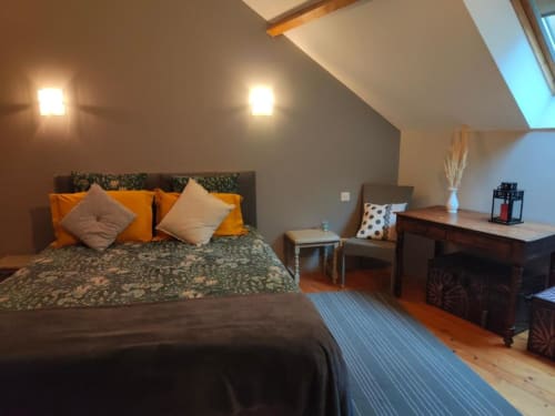 Chambre spacieuse à la villa La Conciergerie de Nathalie à Dinan avec lit queen-size, accents orange, puits de lumière et vue sur le jardin