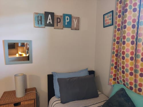 Chambre cosy à La Conciergerie de Nathalie à Dinan avec enseigne "HAPPY", rideaux à pois colorés et confortable