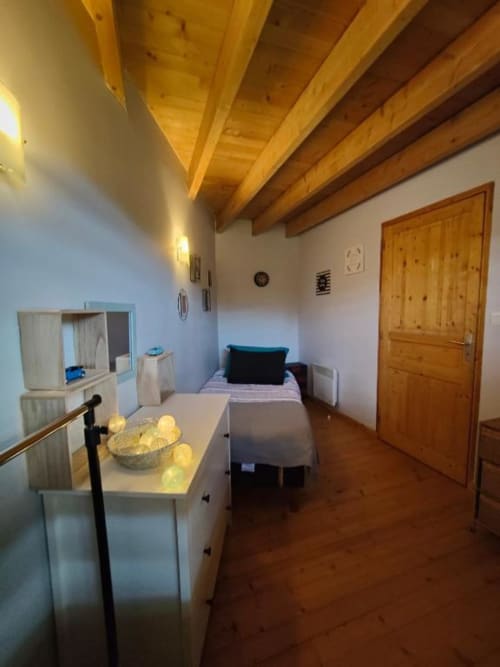 Chambre moderne à La Conciergerie de Nathalie à Dinan avec poutres en bois, lit, bureau et porte en bois