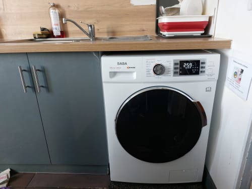 Cuisine moderne avec lave-linge SABA blanc, armoires grises, plan de travail en bois et évier dans l'appartement NancyRoom