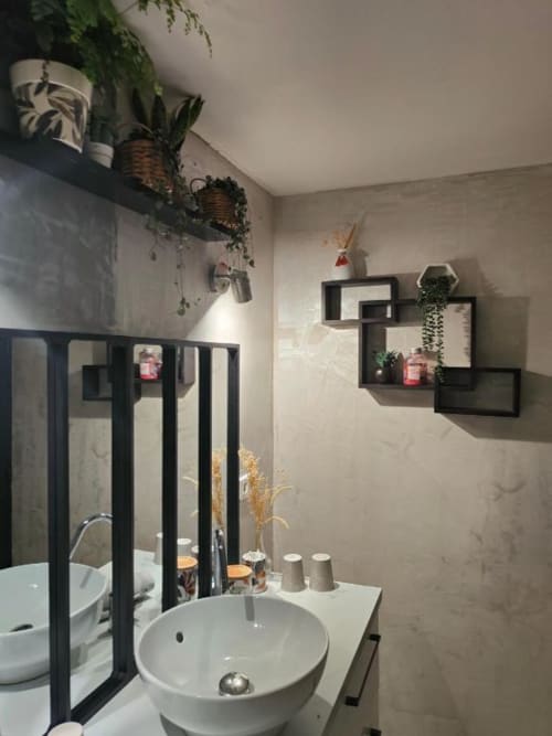 Salle de bains moderne à la villa Gite de la Tannerie avec lavabo blanc rond, étagères noires, plantes murales et porte miroir