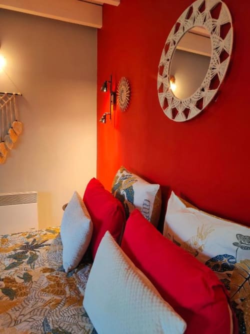 Chambre rouge éclatante à La Conciergerie de Nathalie à Dinan avec miroir décoratif blanc moderne et coin salon confortable