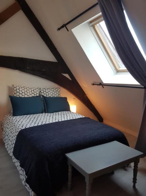 Chambre mansardée chaleureuse à La Conciergerie de Nathalie à Dinan avec poutres apparentes, lucarne et vue sur la ville