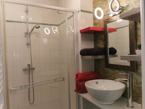 Salle de bain moderne de l'appartement Ty Clement à La Conciergerie de Nathalie, Dinan avec douche, vasque et accents rouges