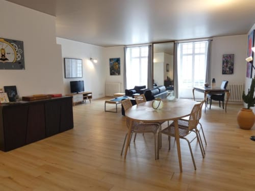 Spacieux appartement DUPLEX à Dinan avec coin repas, chaises en bois, mobilier moderne et vue sur la ville depuis le balcon