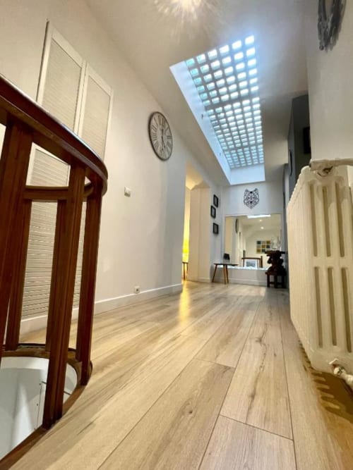 Couloir moderne et lumineux à La Conciergerie de Nathalie à Dinan avec puits de lumière, parquet et mobilier élégant