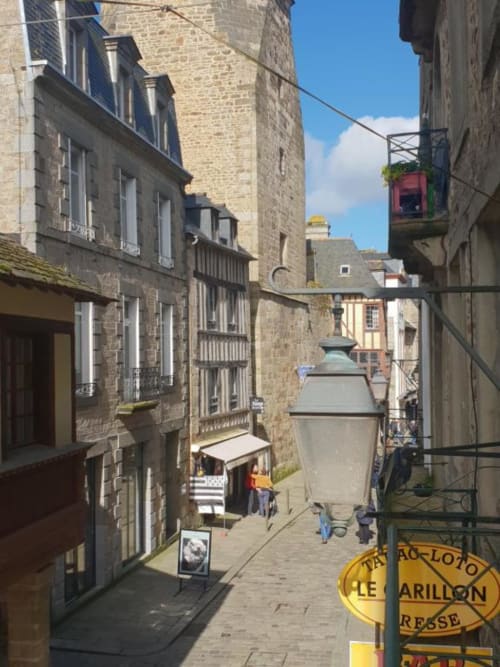 Charmante rue pavée à Dinan avec bâtiments historiques en pierre, panneau jaune et piétons - Studio du Marché