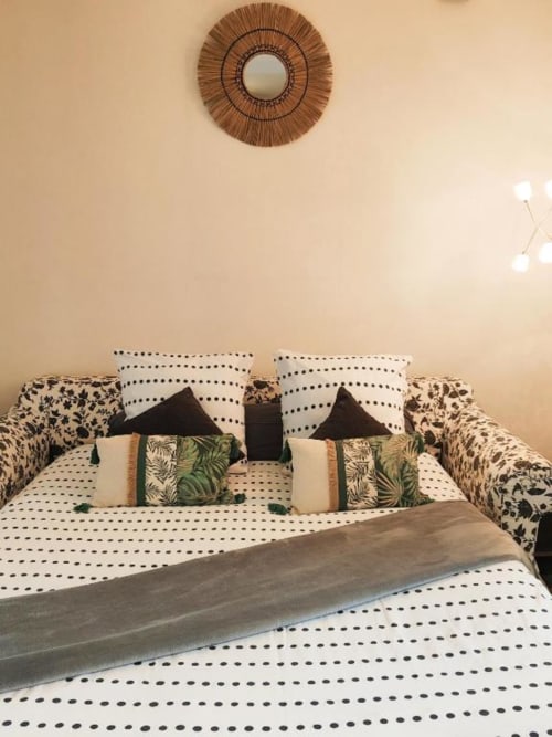 Studio cosy à Dinan avec lit à motifs, coussins décoratifs et miroir tissé au mur