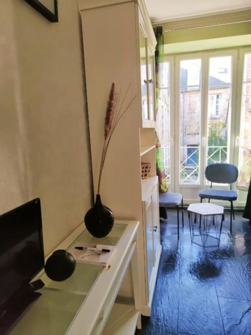 Studio à Dinan avec vue sur la ville, vases noirs décoratifs, parquet bleu et portes-fenêtres sur balcon