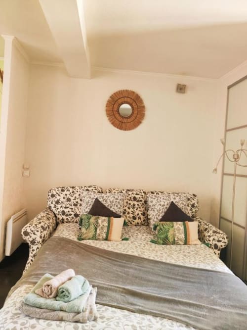 Studio cosy à La Conciergerie de Nathalie à Dinan avec canapé à motifs, serviettes soigneusement rangées et miroir rond