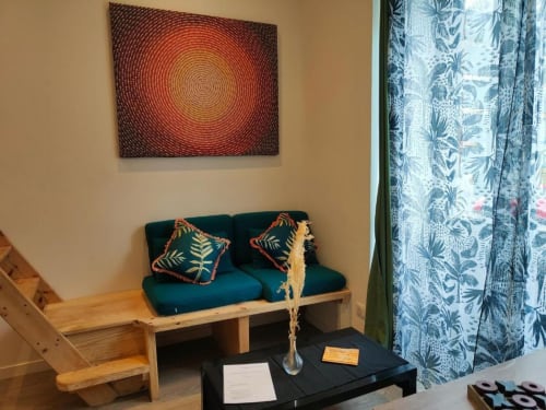 Studio à Dinan avec canapé bleu-vert, art mural circulaire, rideaux à motifs et table noire