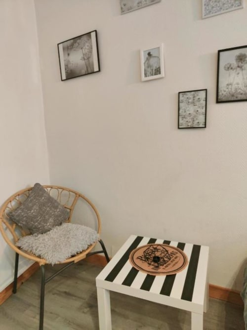 Coin salon cosy de l'appartement Ty Rose à La Conciergerie de Nathalie, Dinan avec fauteuil en rotin et table d'appoint rayée