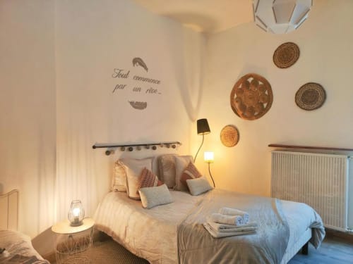 Chambre douillette à La Conciergerie de Nathalie à Dinan avec assiettes murales décoratives, éclairage chaleureux et literie confortable