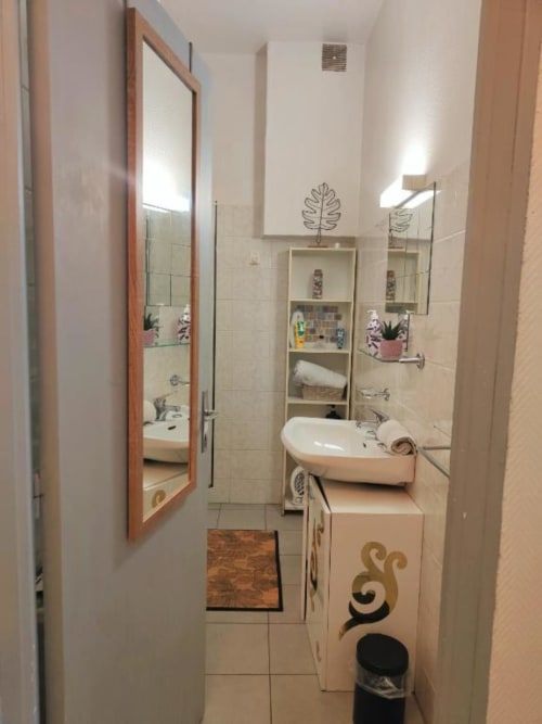 Salle de bain moderne de l'appartement Ty Rose à La Conciergerie de Nathalie, Dinan avec lavabo blanc, miroirs et étagères de rangement