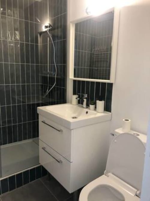 Salle de bain moderne de l'appartement Bohème à La Conciergerie de Nathalie, Dinan avec douche carrelée noire, vasque blanche et