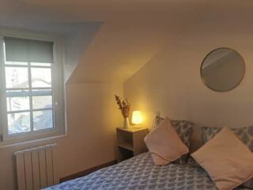 Chambre douillette de l'appartement Bohème à La Conciergerie de Nathalie, Dinan, avec éclairage chaleureux et vue sur la ville