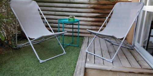 Coin détente du studio jardin à La Conciergerie de Nathalie à Dinan avec deux transats et table d'appoint turquoise