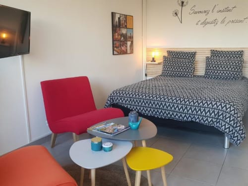 Studio moderne à La Conciergerie de Nathalie à Dinan avec lit, sièges colorés et vue sur jardin