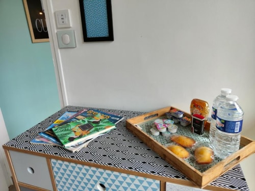 Plateau de bienvenue avec viennoiseries, eau et livres au studio-jardin La Conciergerie de Nathalie à Dinan