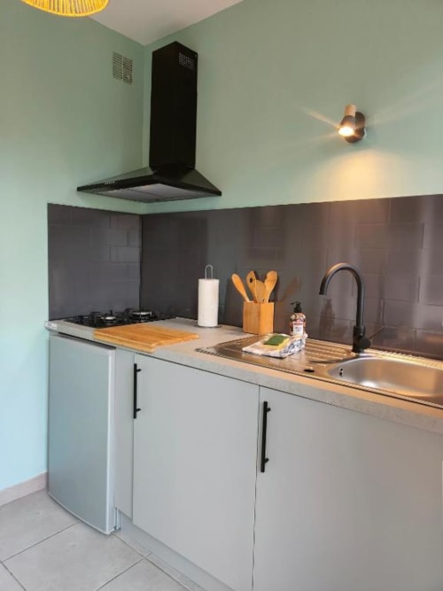 Kitchenette moderne au Garden Studio de La Conciergerie de Nathalie, Dinan avec armoires blanches, cuisinière noire et inox