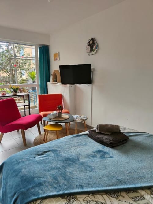 Studio moderne à La Conciergerie de Nathalie à Dinan avec vue sur jardin, TV, chaises rouges et lit bleu