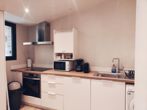 Kitchenette moderne à la Villa Hortense de La Conciergerie de Nathalie, Dinan avec meubles blancs, électroménager noir et bois