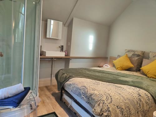 Chambre moderne à La Conciergerie de Nathalie à Dinan avec lit, oreillers jaunes, salle de bain attenante et parquet