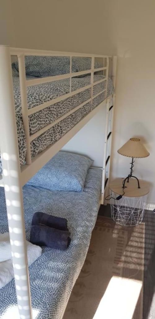 Chambre douillette dans un appartement de Dinan avec lits superposés intégrés, literie rayée et table de nuit avec lampe