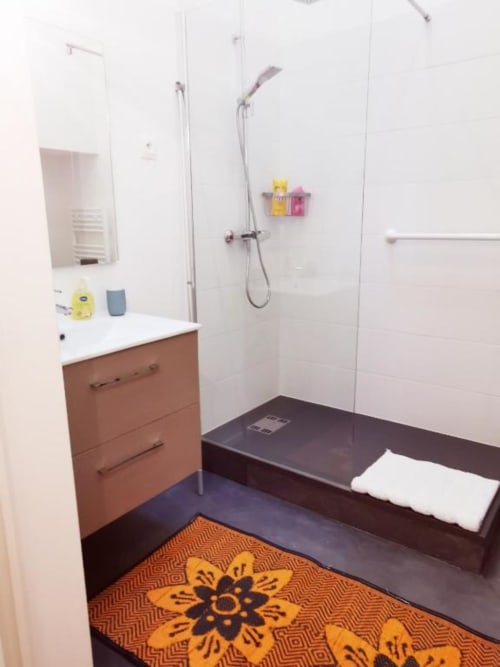 Salle de bain moderne à La Conciergerie de Nathalie, Dinan avec douche à l'italienne, meuble vasque en bois et tapis orange décoratif