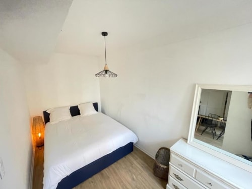 Chambre moderne à La Conciergerie de Nathalie à Dinan avec literie blanche, suspension et armoire miroir