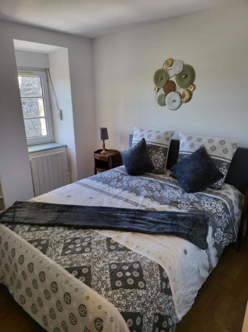 Chambre douillette à La Conciergerie de Nathalie à Dinan avec literie à motifs, coussins bleus et décoration murale