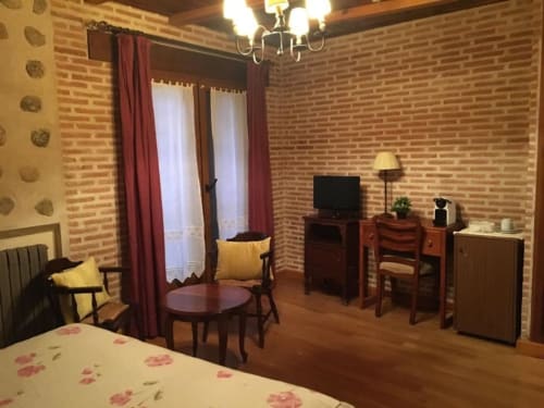 Hotel Santorini Belgrade bedroom with brick walls, double bed, TV, desk, and red curtains