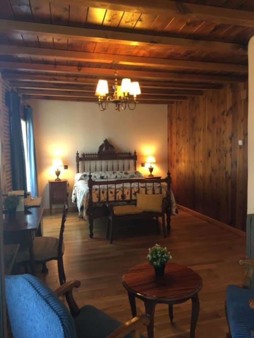 Elegant bedroom at Hotel Santorini Belgrade with black metal bed, wooden beams, warm lighting, and classic furnishings