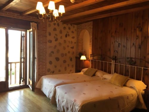 Habitación rústica en Hotel Santorini Belgrade con vigas de madera, paredes de ladrillo y cama de hierro