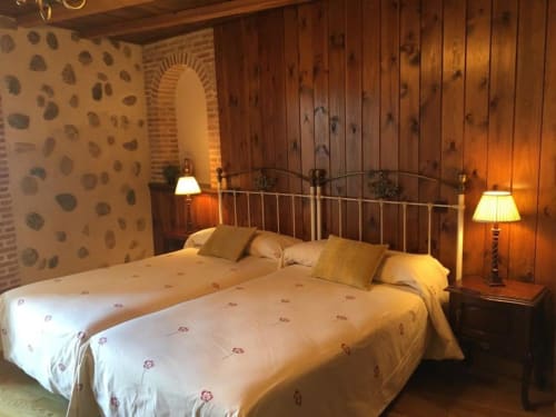 Acogedora habitación del Hotel Santorini Belgrade con vigas de madera, cama de marco metálico e iluminación cálida