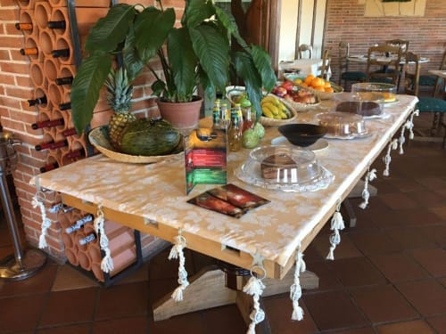 Mesa de comedor del Hotel Santorini Belgrade con frutas frescas, plantas y borlas blancas decorativas para un desayuno acogedor