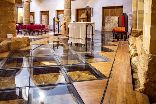 La hall del Stella Marina a Porto Empedocle presenta antiche rovine in pietra, pavimenti in vetro, sedute rosse e stile moderno