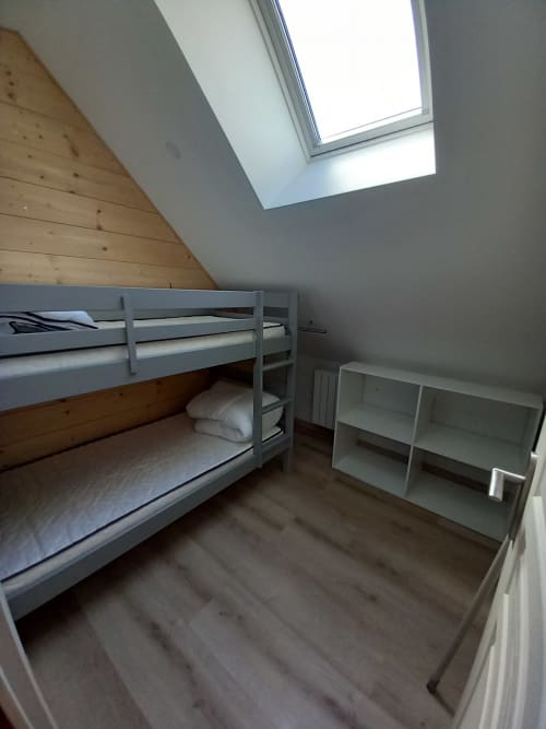 Chambre mansardée à la villa La Maison De Fleurat avec lit superposé, lucarne, poutres en bois et étagères de rangement