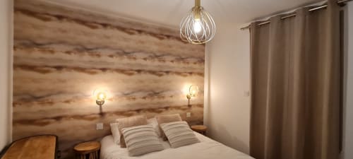 Cozy bedroom at Relais des Iles cottage in Saint-Marcouf with wooden accent wall, striped pillows, pendant light, and wall