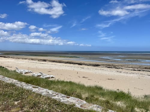 Sandy beach at Relais des Iles in Saint-Marcouf with boats, sea view, and blue sky