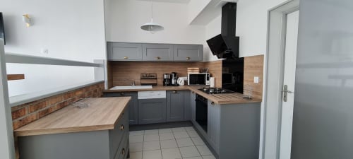 Cuisine moderne équipée du gîte La Plage à RELAIS DES ÎLES, Saint-Marcouf, avec armoires grises, plan de travail en bois et