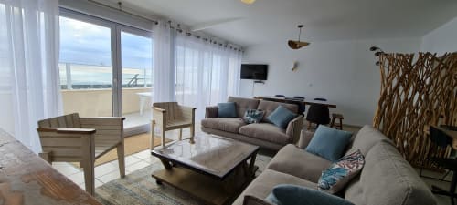 Modern cottage living room with sea views, comfortable seating, and terrace access at Relais des Îles, Saint-Marcouf