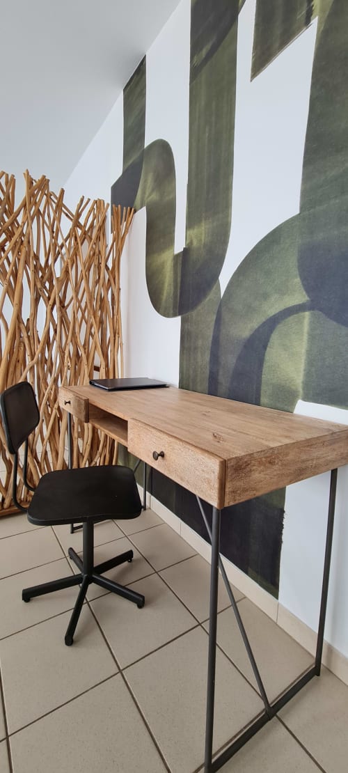Modern workspace at RELAIS DES ILES cottage with wooden desk, black chair, woven room divider, and saguaro cactus wall mural