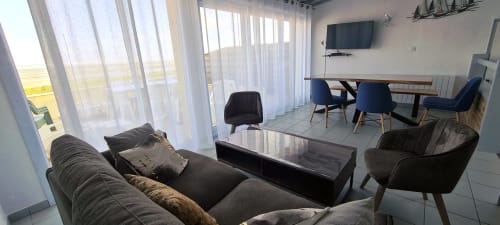 Modern cottage living room with sea view, comfortable seating, TV, and dining area at Relais des Îles, Saint-Marcouf