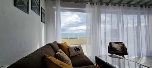 Modern cottage living room with sea view terrace overlooking Saint-Marcouf coastline, featuring comfortable seating and