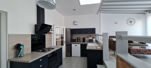 Modern kitchen in Gîte Les Embruns cottage at Relais des Îles, Saint-Marcouf with black appliances and light wood countertops