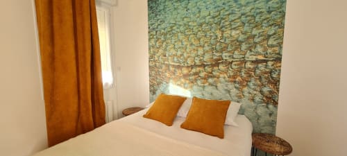 Cozy bedroom at Relais des Iles cottage in Saint-Marcouf with orange pillows, rustic stone accent wall, and sea view curtains