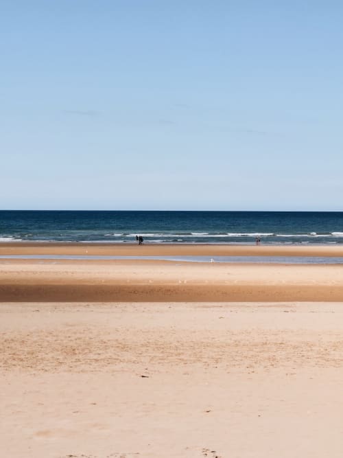 Serene sandy beach with calm waters at Relais des Îles, Saint Marcouf France
