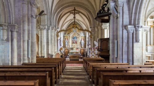 Historic church interior with wooden pews, ornate altar, and vaulted arches in Saint Marcouf, France