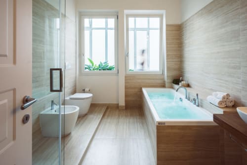Bagno della Jacuzzi Suite Bluemoon Sardinia con vasca relax, doccia walk-in e vista sulla città di Cagliari